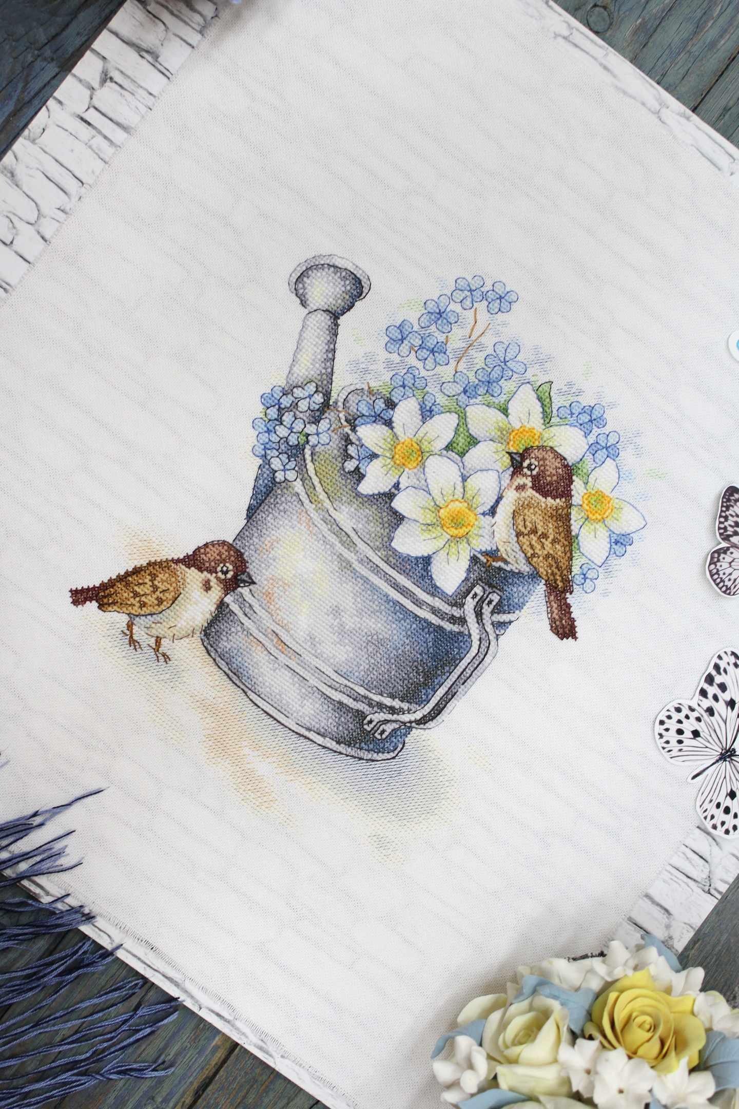 Daffodil Lovers SA-026 Cross-stitch kit featuring a watering can, white chamomiles, blue flowers, and a bullfinch on 27 count canvas.